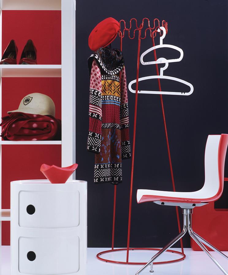 Retro Cloakroom Furniture In Red And White With Coat Hangers And Coat Rack Against Dark Wall Photograph by Matteo Manduzio