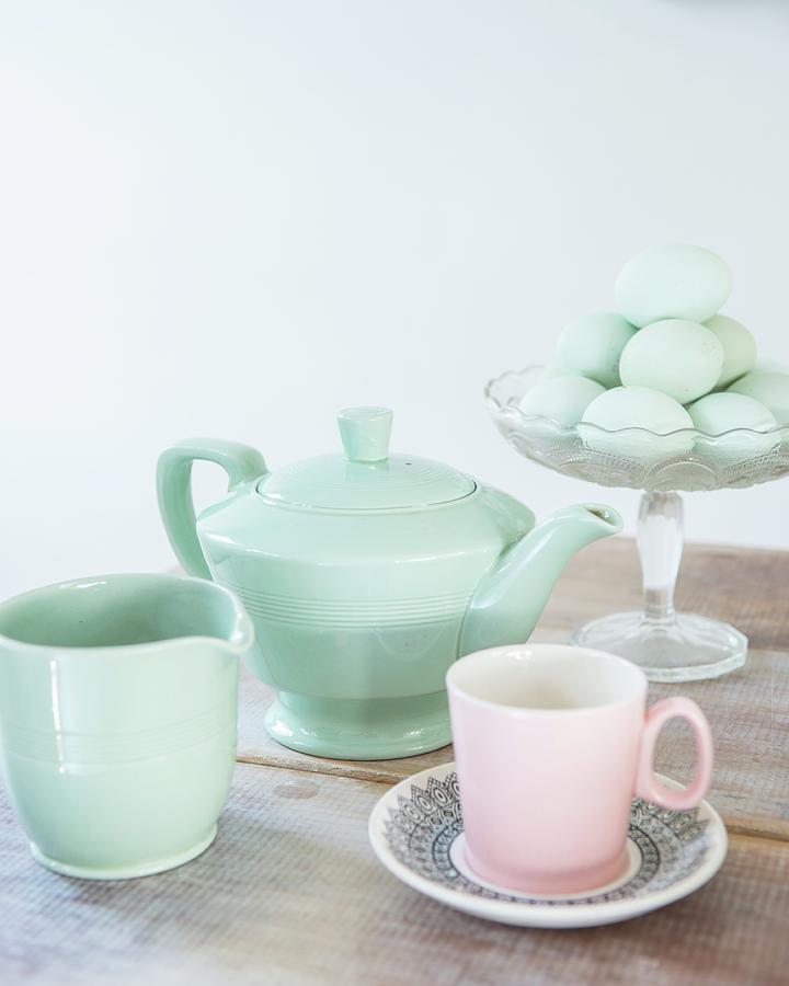 Retro Teapot, Milk Jug And Pink Teacup In Front Of Eggs In Glass Bowl Photograph by Stuart Cox