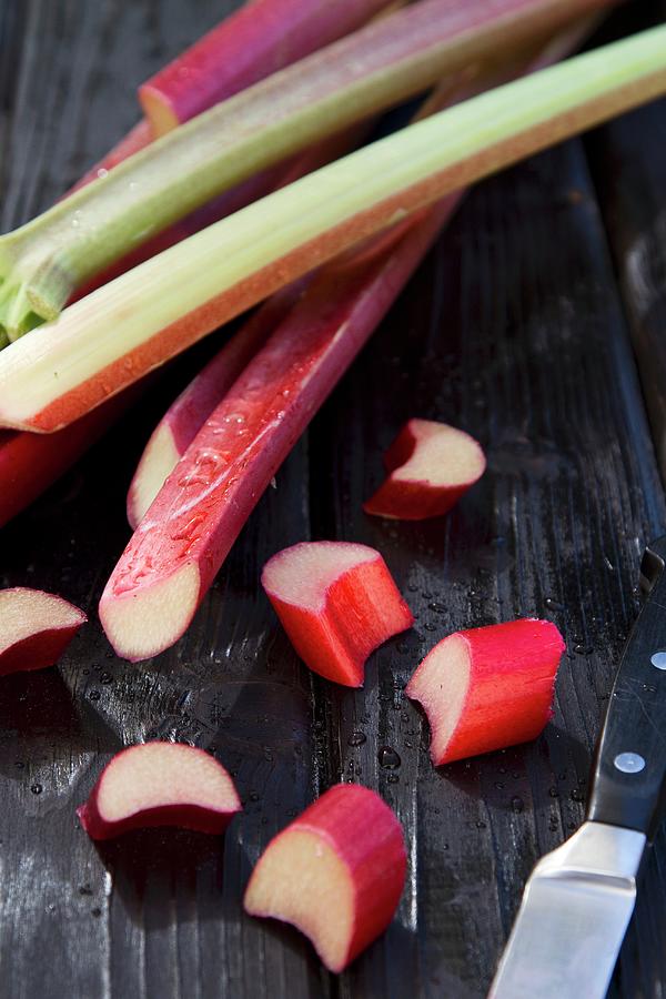 Rhubarb Stalks On A Wooden Surface, Some Partially Sliced Photograph by Catja Vedder