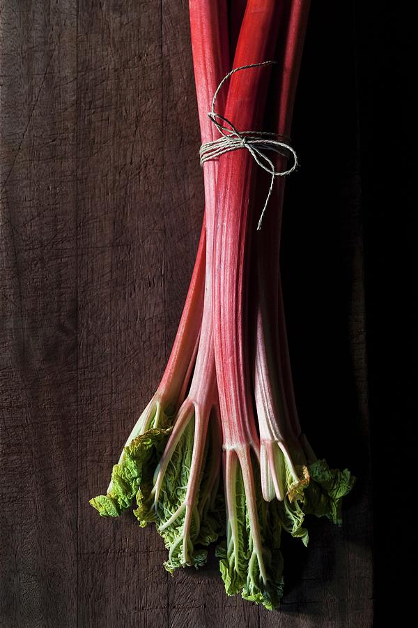 Rhubarb Stalks, Tied In A Bundle, On A Wooden Surface Photograph by Sarah Coghill