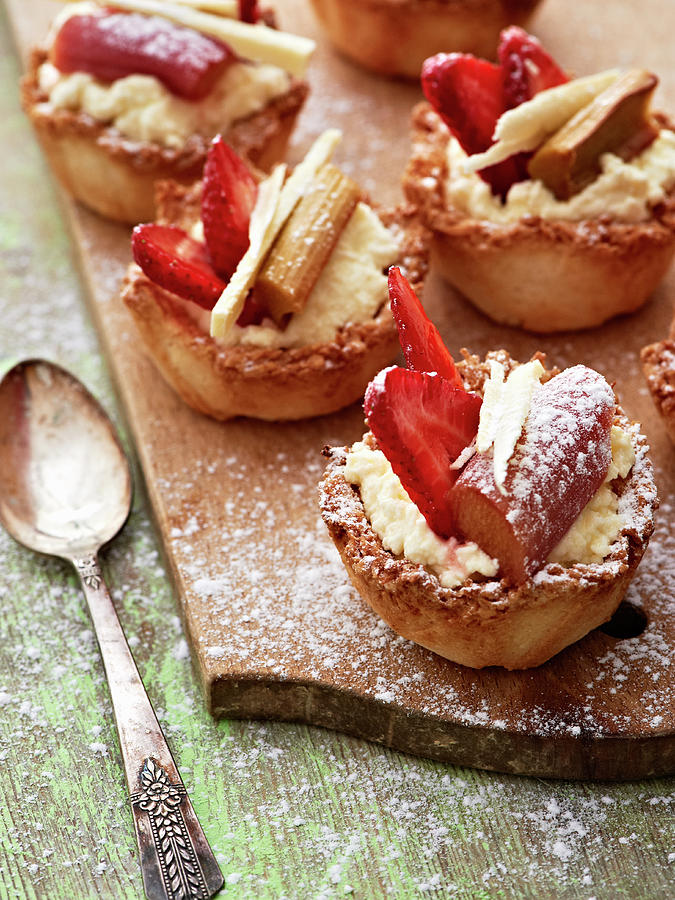Rhubarb, Strawberry And Coconut Tartlets On A Wooden Board Photograph by Hannah Kompanik