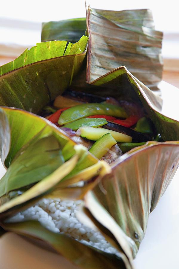 Rice, Courgette, Peas, Peppers And Onions In A Banana Leaf Photograph by Studio Lipov