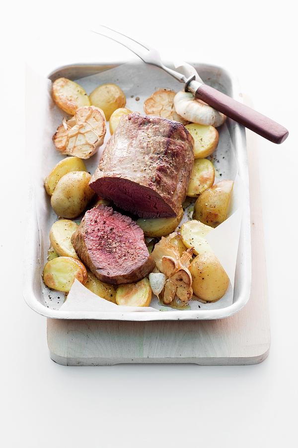Roast Fillet Of Beef With Potatoes And Garlic Photograph by Michael Wissing