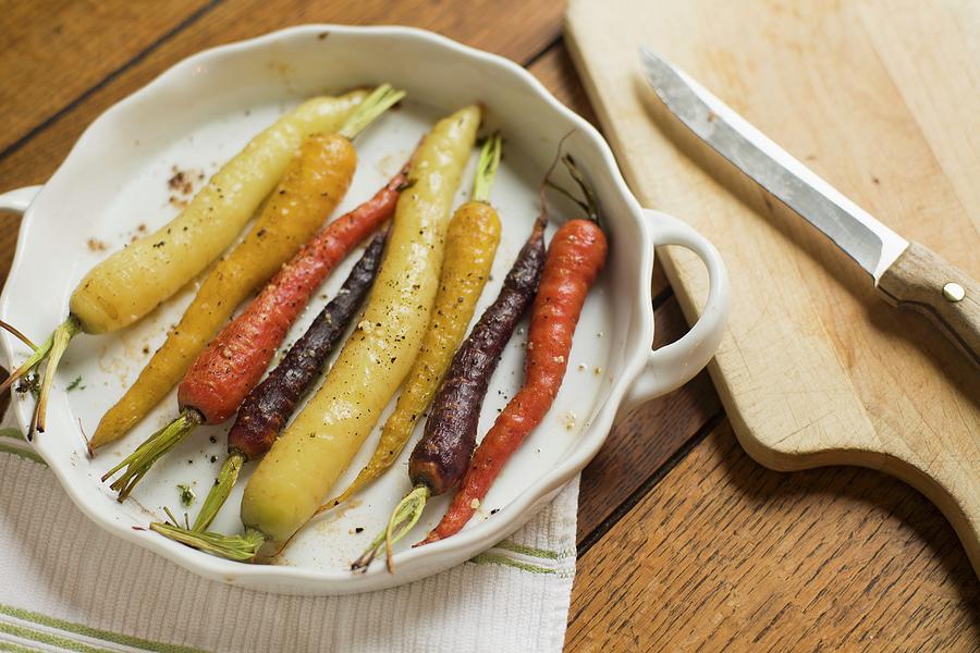 Roasted Multi-color Carrots In A White Scalloped Dish With Knife And Cuting Board Photograph by Don Crossland