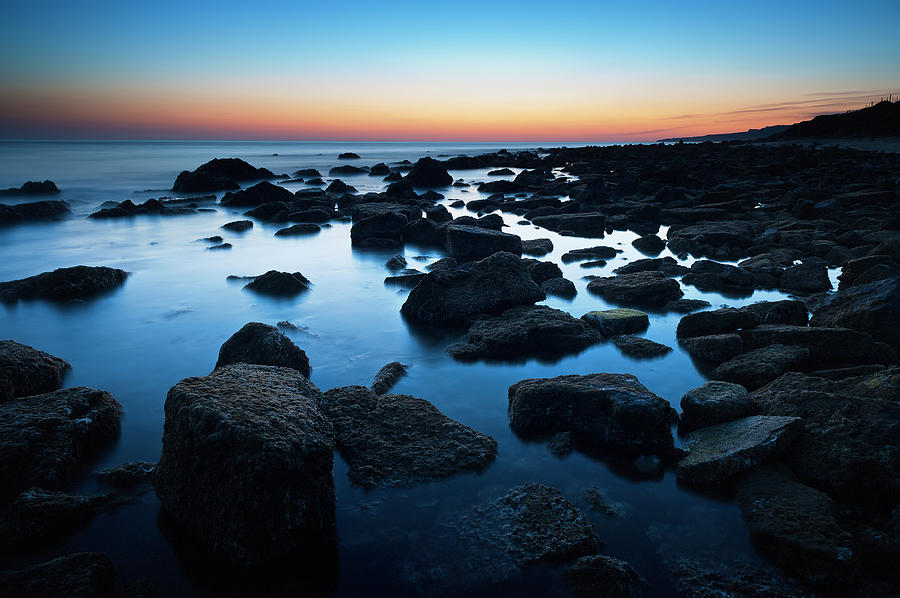 Rocks In The Tranquil Water Along The Photograph by Ben Welsh / Design Pics