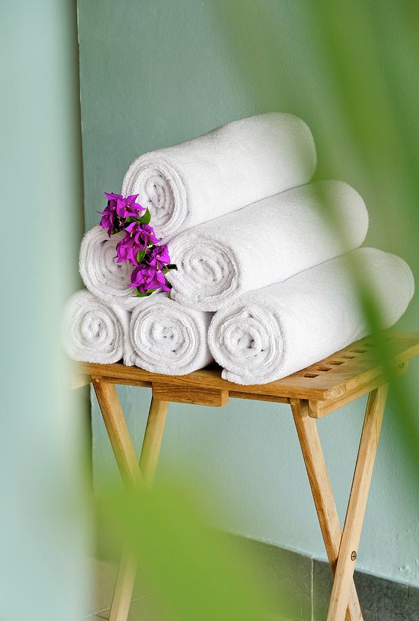 Rolled Bath Towels Decorated With Flowers On A Small, Wooden Table Photograph by Anthony Lanneretonne