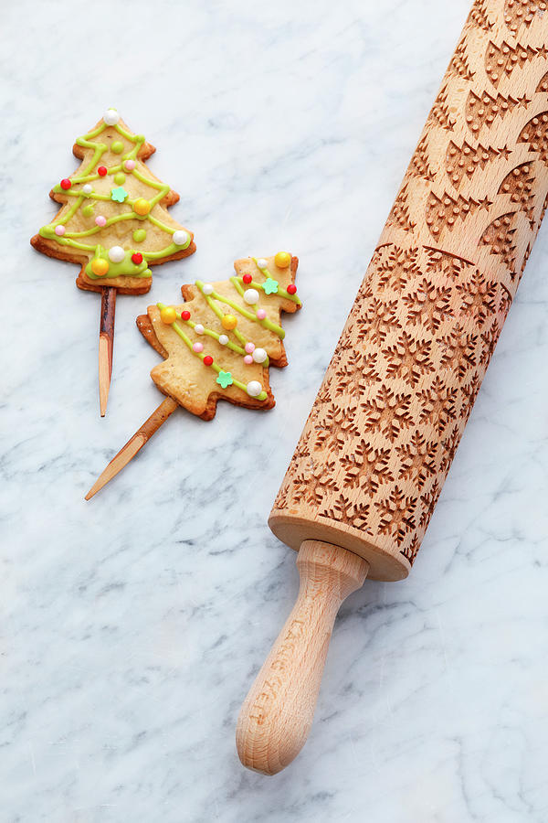 Rolling Pin With Christmas Motifs And Christmas Tree Biscuits On A Stick Photograph by Mathias Stockfood Studios / Neubauer