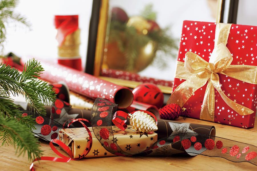 Rolls Of Wrapping Paper And Ribbons Next To Wrapped Christmas Present With Bow Photograph by Biglife