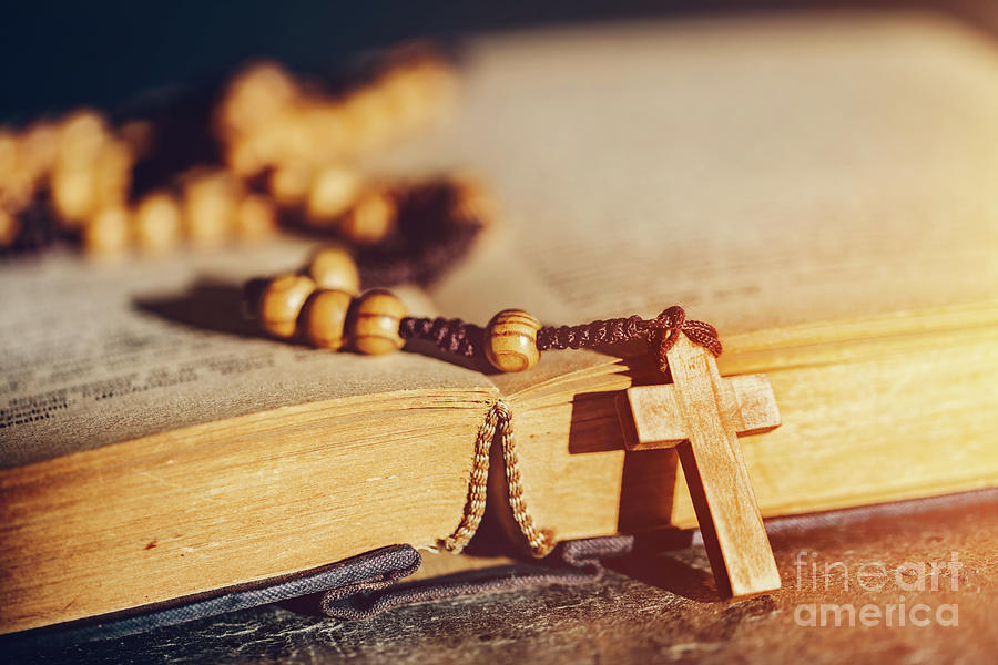Rosary with cross laying on a Bible book. Photograph by Michal Bednarek