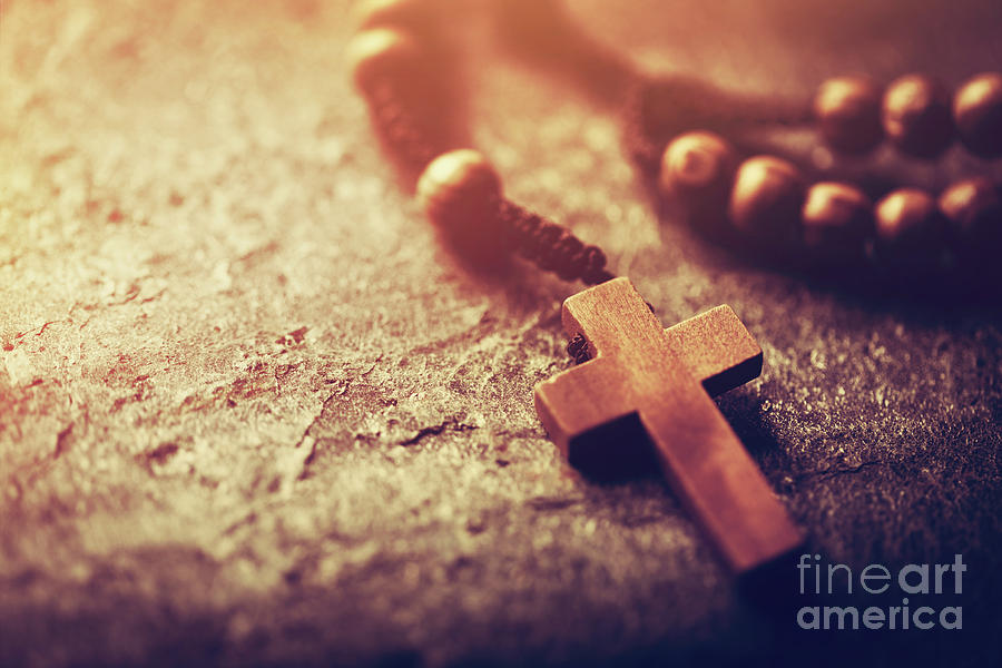 Rosary with wooden cross on stone background. Photograph by Michal Bednarek