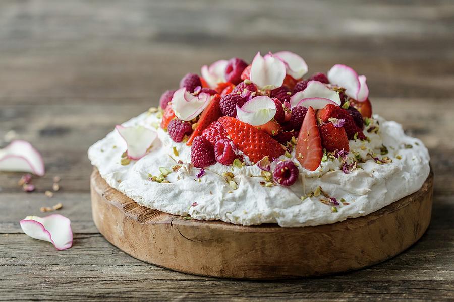 Rose And Pistachio Pavlova With Fresh Strawberries And Raspberries, Decorated With Pistachio Nuts And Dried And Fresh Rose Petals On A Wooden Surface Photograph by Sarah Coghill