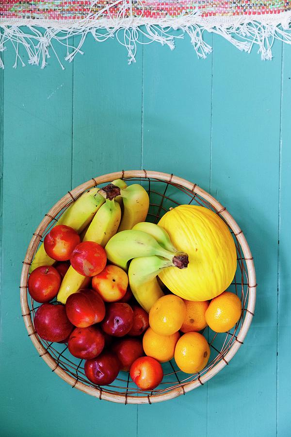 Round Basket Of Fruit On Blue Wooden Floor Photograph by Jenny Brandt