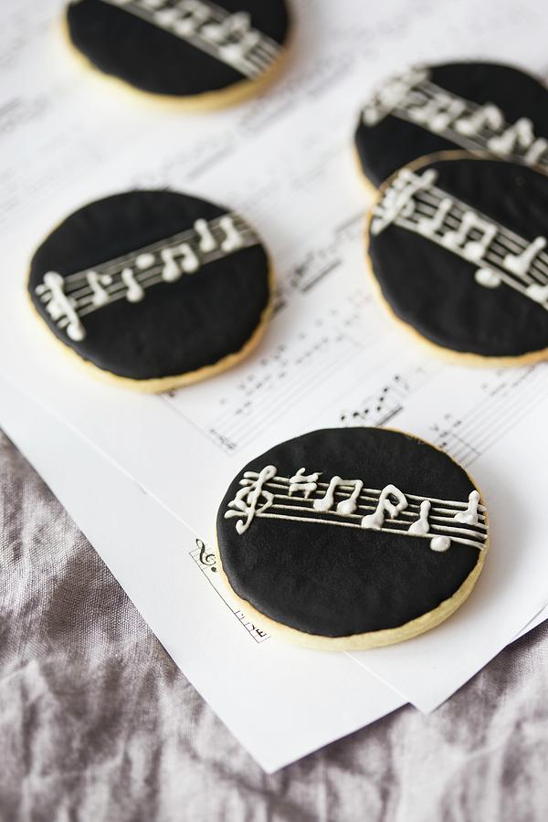 Round Cookies With Black Icing On A Piece Of Sheet Music Photograph by Malgorzata Laniak