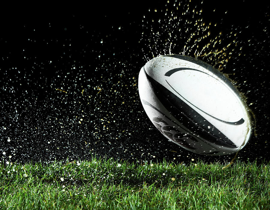 Rugby Ball In Motion Over Grass Photograph by Thomas Northcut