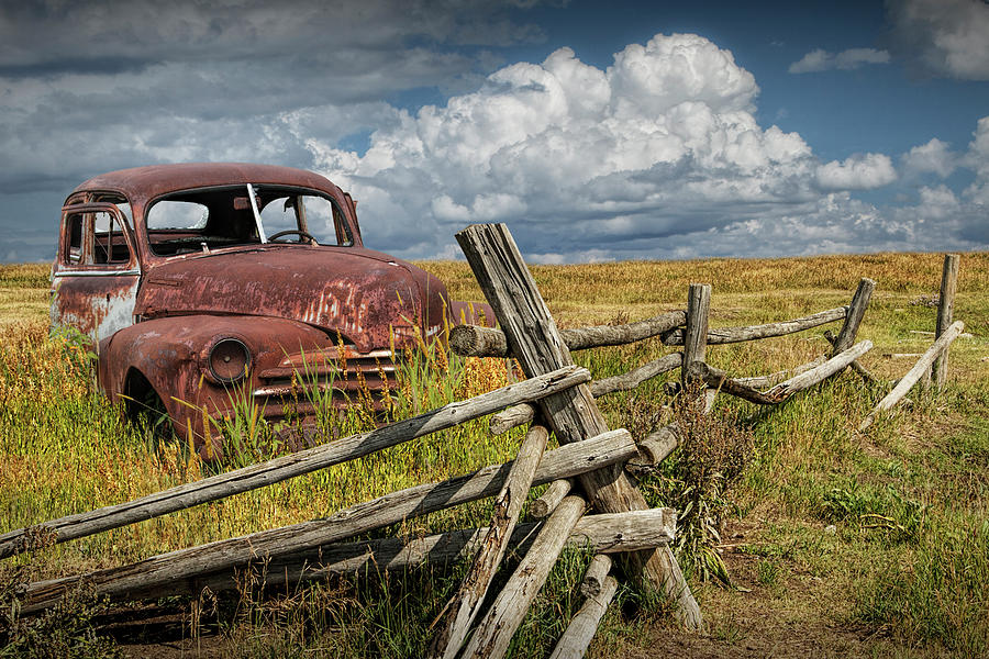 Rusted Vintage Automobile in a Rural Landscape behind Old Wooden Log Fence Photograph by Randy Nyhof
