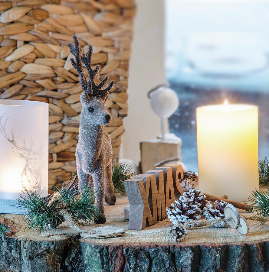 Rustic Christmas Arrangement Of Reindeer Figurine, Candle, Lantern And Pine Cones On Slice Of Tree Trunk Photograph by Chris Schfer