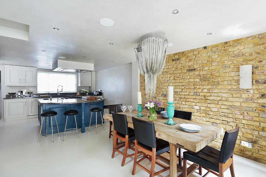 Rustic, Solid Wood Dining Table With Elegant Black Chairs In Front Of Brick Wall Below Pendant Lamp Shaped Like Icicles Photograph by Simon Maxwell Photography