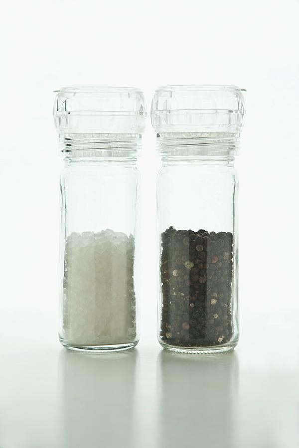Salt And Pepper In Plexiglass Mills On A White Surface Photograph by William Boch