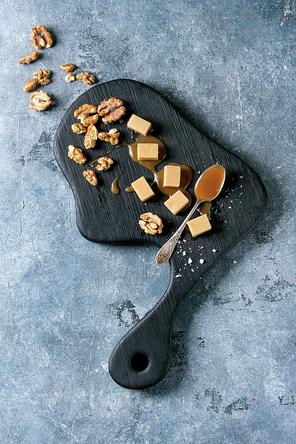 Salted Caramel Fudge Candy Served On Black Wooden Board With Fleur De Sel, Caramel Sauce And Caramelized Walnuts Photograph by Natasha Breen