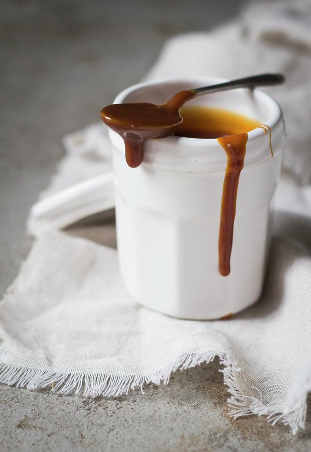 Salted Caramel Sauce In A Cot With A Spoon Photograph by The Kate Tin