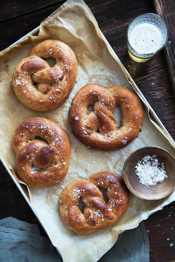 Salted Pretzels On A Baking Tray, And A Glass Of Beer Photograph by Veronika Studer
