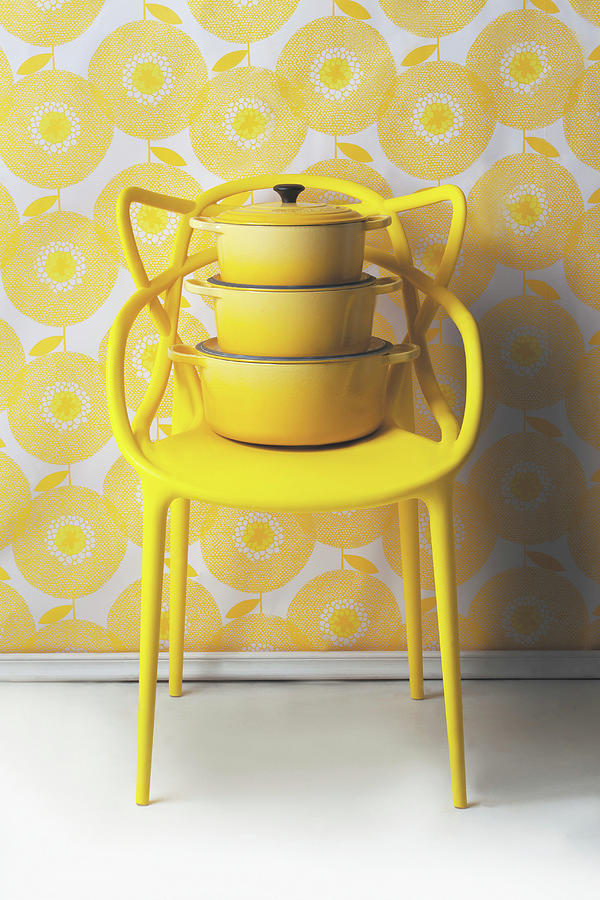 Saucepans Stacked On Yellow Designer Chair Against Yellow And White Wallpaper Photograph by Great Stock!