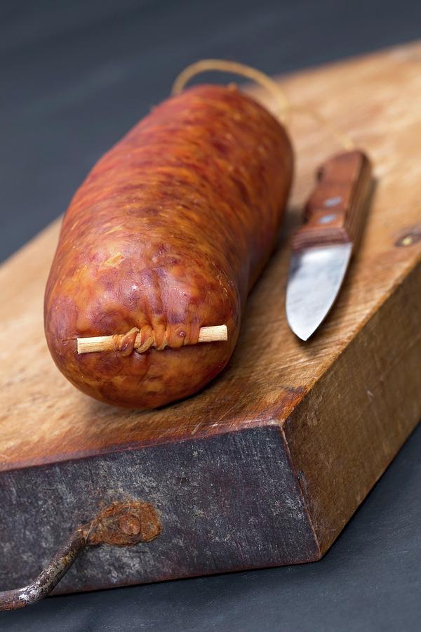 Saucisse De Morteau french Sausage On A Chopping Board With A Knife Photograph by Lydie Besancon