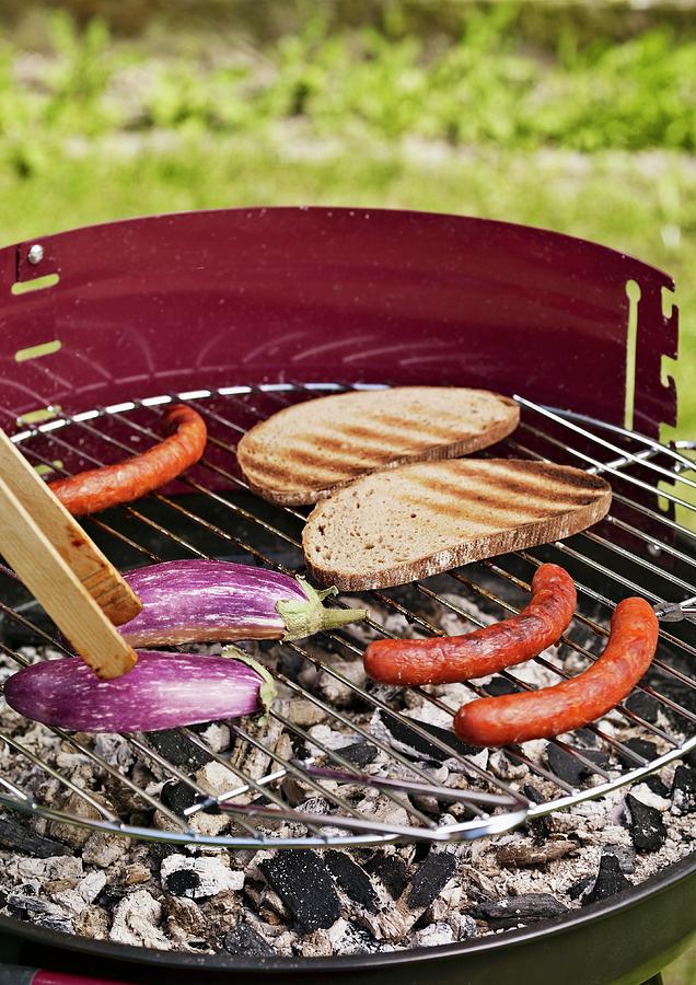 Sausages, Aubergines And Slices Of Bread On A Barbecue Photograph by Till Melchior