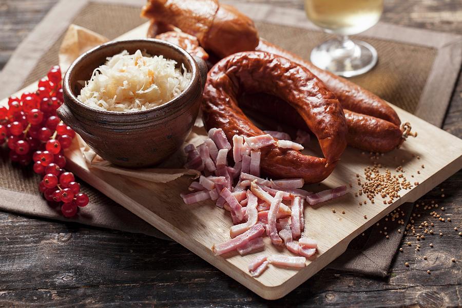 Sausages, Sauerkraut And Bacon Strips On A Wooden Chopping Board Photograph by Malgorzata Stepien