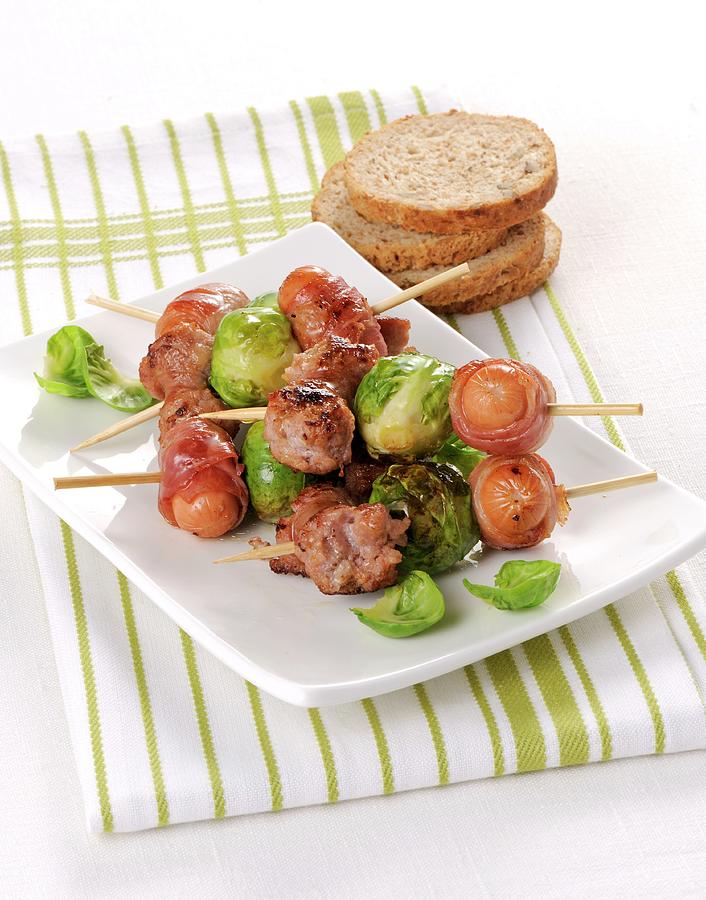 Sausages Wrapped In Bacon And Brussels Sprouts On Skewers Photograph by Franco Pizzochero