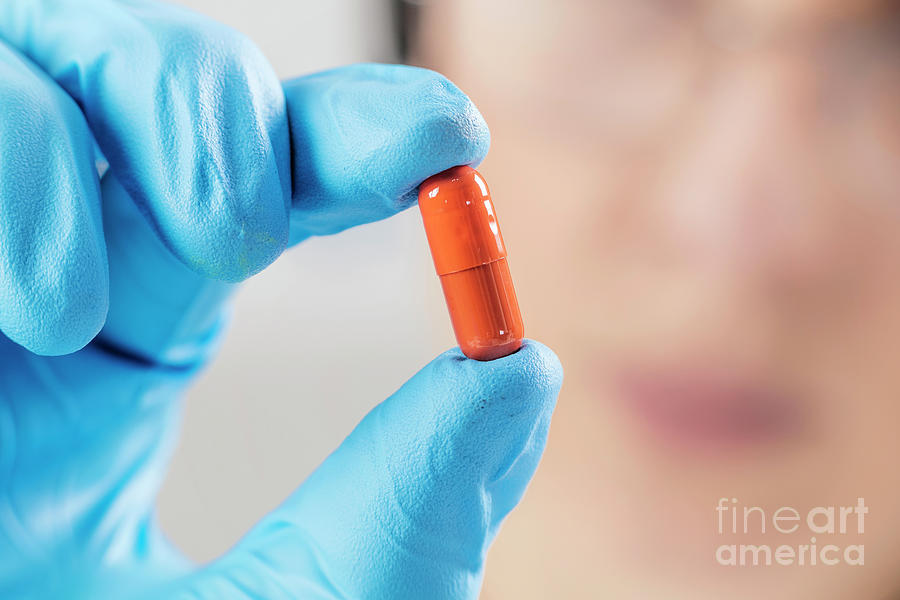 Scientist Holding Orange Pill Photograph by Microgen Images/science Photo Library