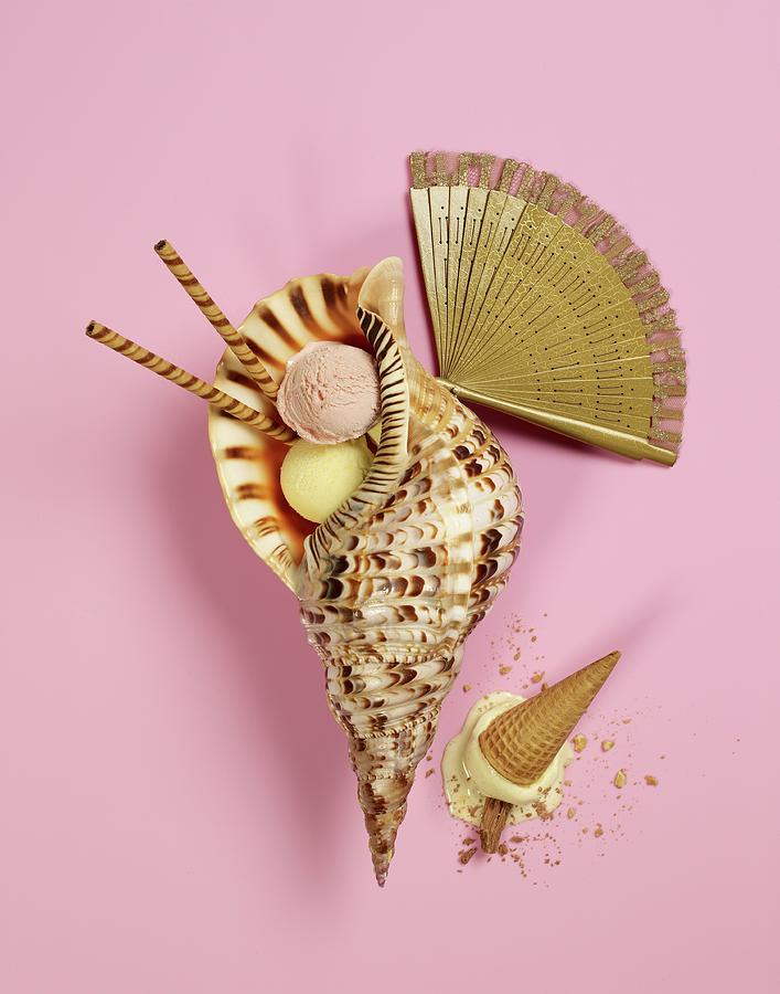 Scoops Of Ice Cream In A Shell Next To A Golden Fan And An Overturned
