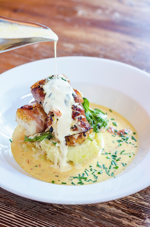 Sea Bass Fish Fillets Wrapped In Bacon On A Potato Mash With Spinach And Chives With A Pour Of White Wine Sauce Photograph by Giulia Verdinelli Photography