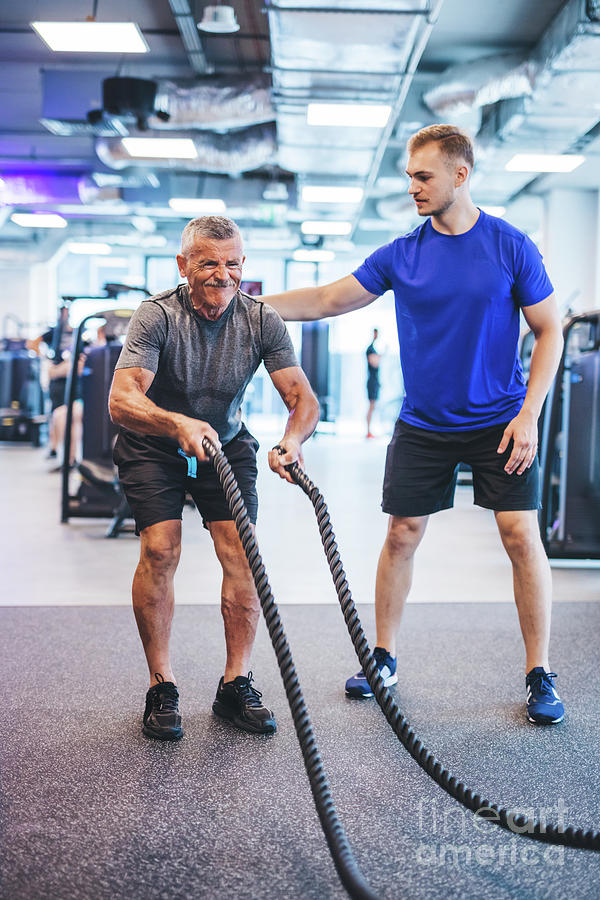 Senior man exercising at the gym with gym instructor. Photograph by Michal Bednarek
