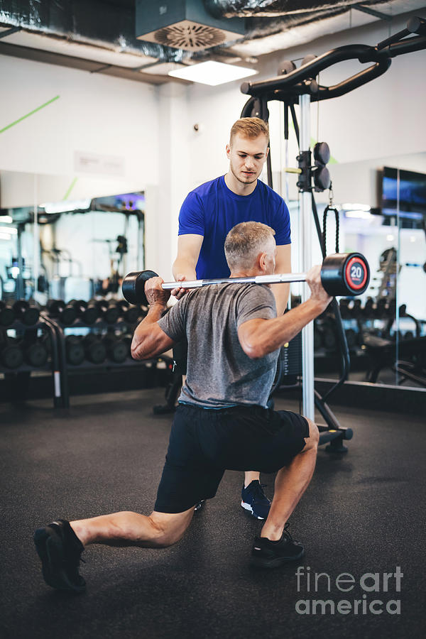Senior man exercising with personal trainer. Photograph by Michal Bednarek