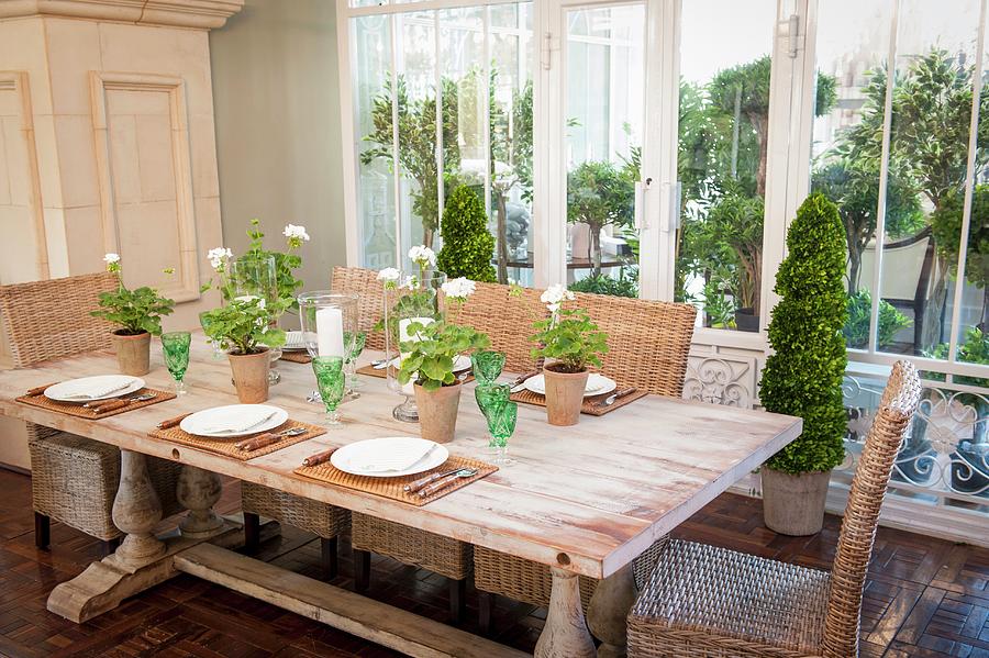 Set Wooden Table, Wicker Chairs, Green Crystal Glasses And Geraniums Photograph by Great Stock!