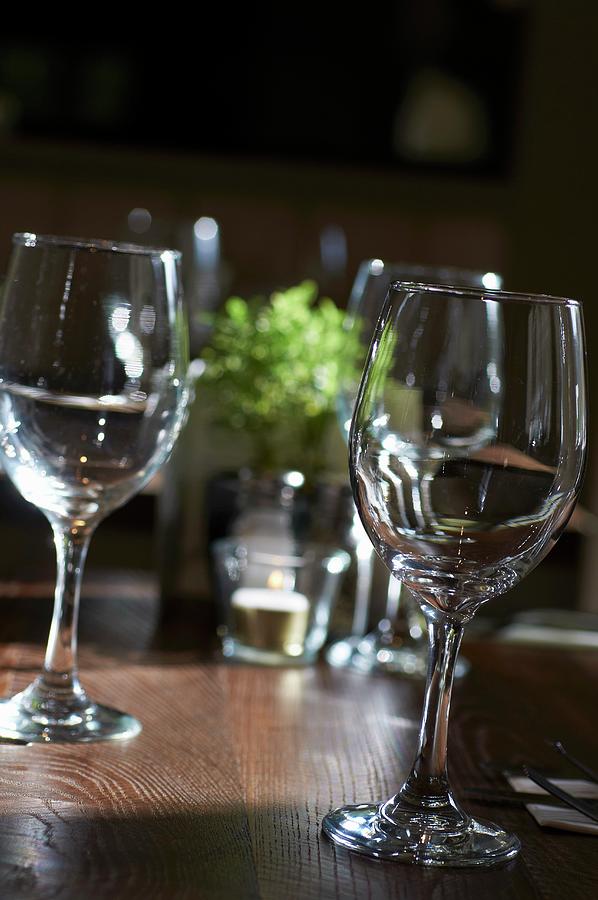 Several Empty Wine Glasses On A Wooden Table In A Restaurant Photograph by Tim Green