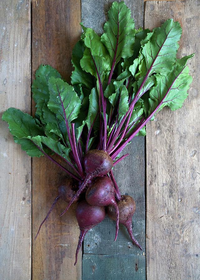 Several Fresh Beetroots With Leaves On A Wooden Background Photograph by Anita Brantley