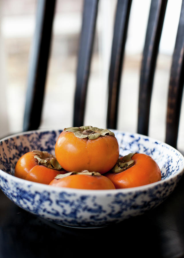 Several Persimmons In A Bowl On A Black Chair Photograph by Ryla Campbell