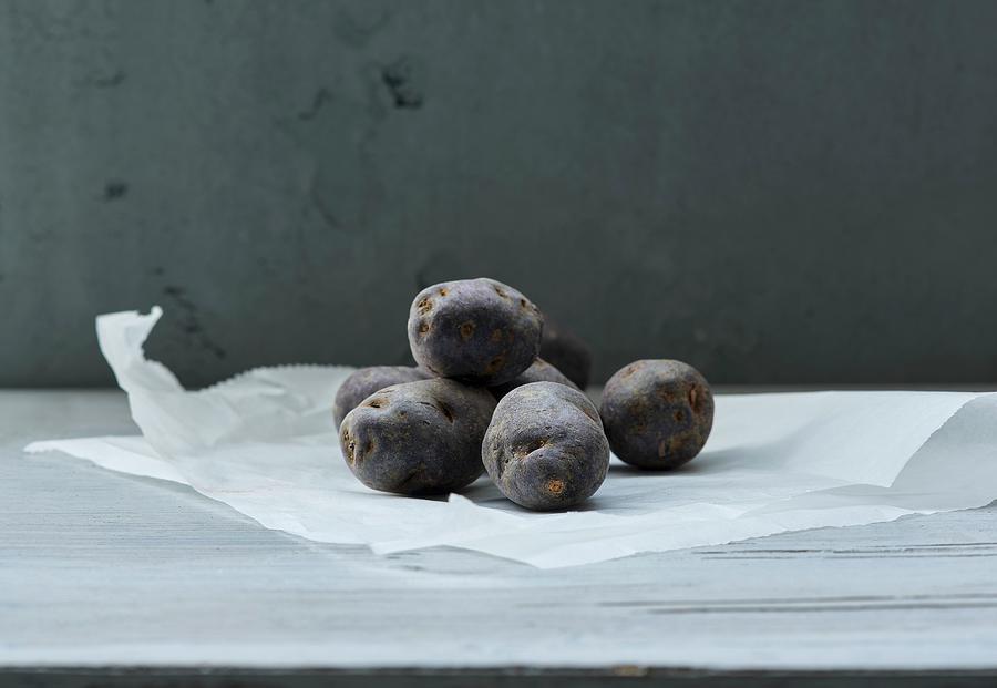 Several Violet Potatoes On A Piece Of Paper Photograph by Stefan Schulte-ladbeck