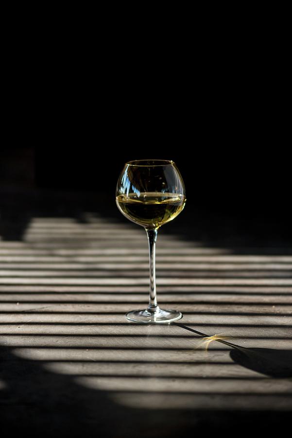 Shadows Playing Over A Glass Of White Wine Photograph by Hein Van Tonder
