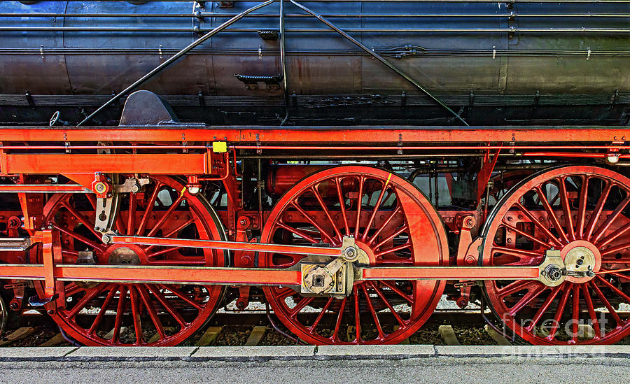 Shiny steam locomotive with bright red wheels stands on rail-road track. Photograph by Ulrich Wende
