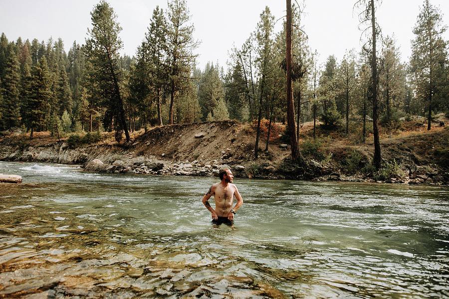 Shirtless Man Looking Away While Standing In River Against Trees At ...