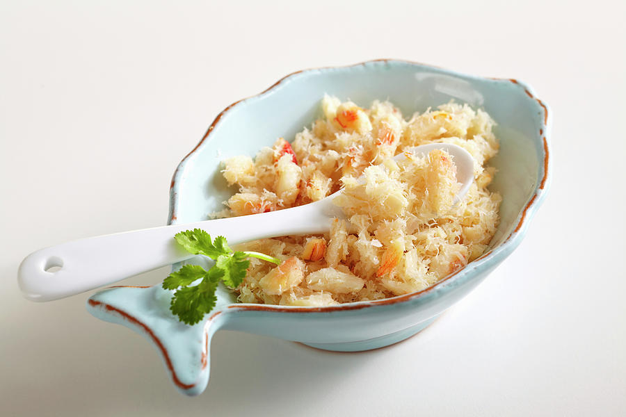 Shredded Crab Meat In A Small Bowl With A Spoon And Coriander Leaves