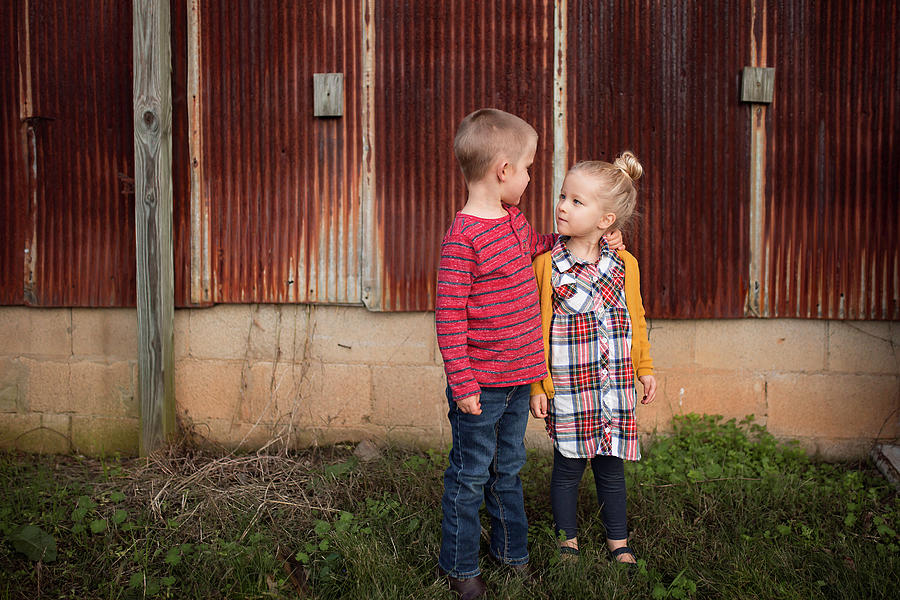 Siblings Looking Each Other Face To Face While Standing Against Abandoned Building On Field 4130