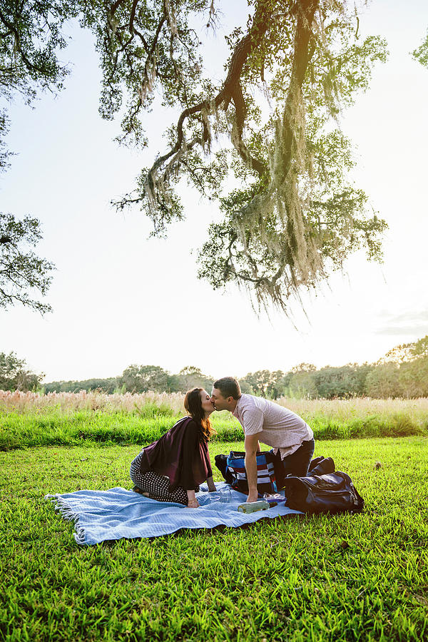 Side View Of Couple Kissing While Kneeling On Blanket At Park ...