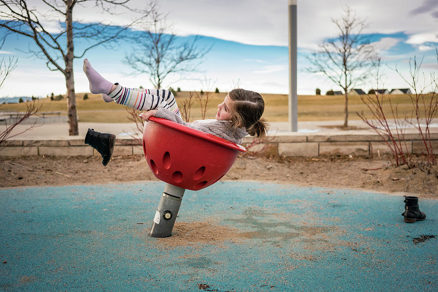 Side View Of Playful Girl Throwing Shoes While Playing On Outdoor Play Equipment Against Cloudy