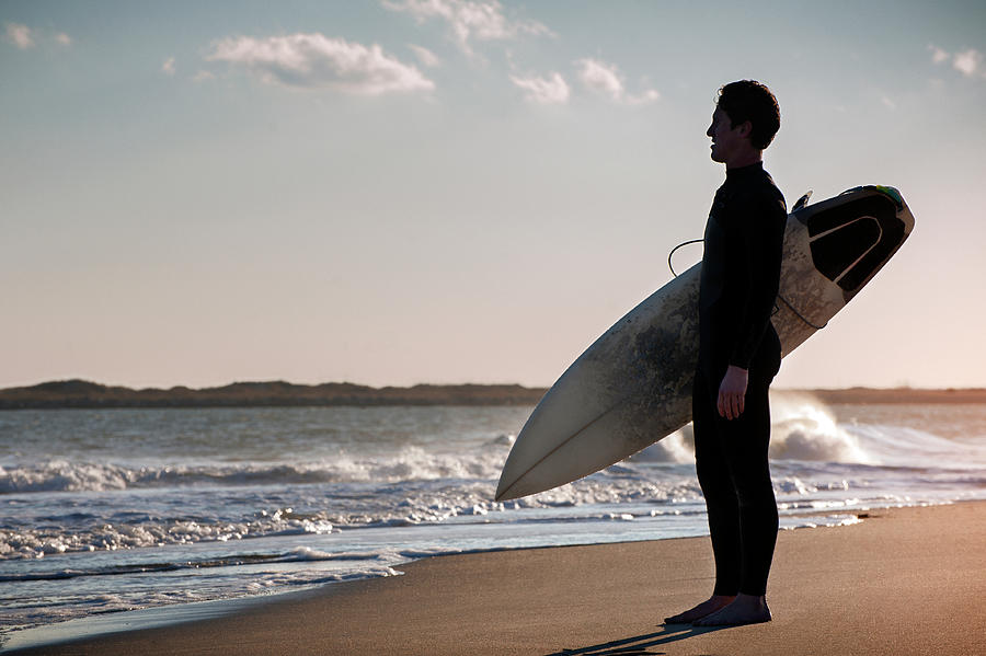 Side View Of Surfer Carrying Surfboard While Standing On Shore ...