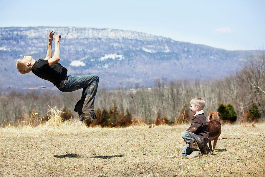 Side View Of Teenage Boy Backflipping On Field Photograph by Cavan ...