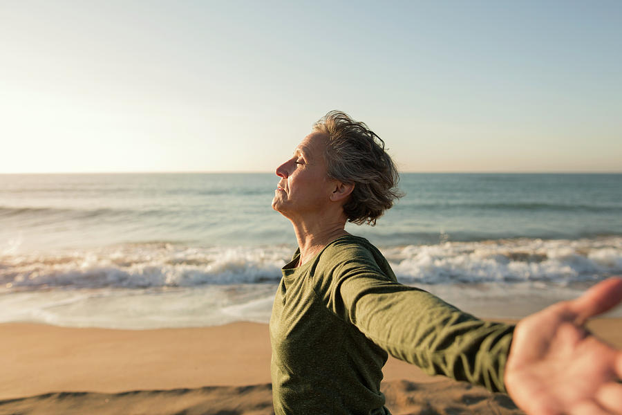 Side View Of Woman With Arms Outstretched At Beach Against Clear Sky 